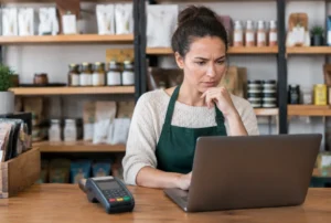 Händlerin prüft Gebühren der Kartenzahlung am Laptop